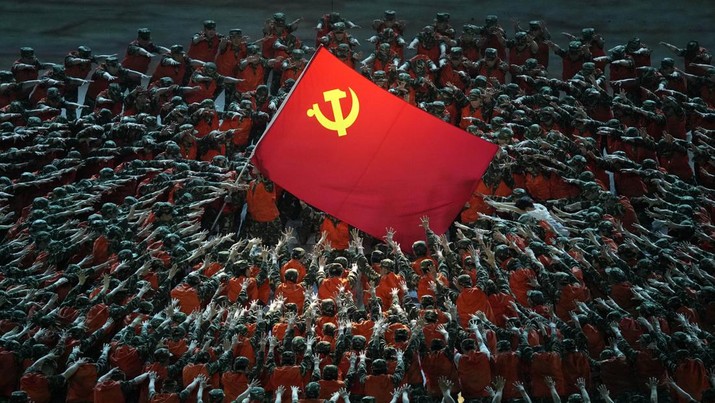 Penampil berpakaian seperti petugas penyelamat berkumpul di sekitar bendera Partai Komunis selama pertunjukan gala menjelang peringatan 100 tahun berdirinya Partai Komunis China di Beijing (28/6/2021). (AP Photo/Ng Han Guan)