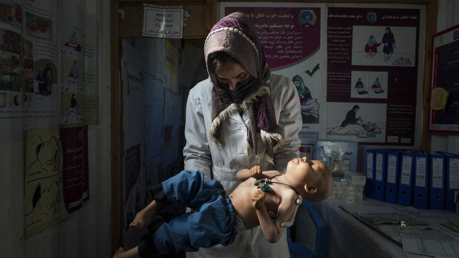 Seorang perawat memeriksa berat badan seorang anak di klinik darurat yang didirikan oleh World Vision di sebuah pemukiman dekat Herat, Afghanistan (16/12/2021). Malnutrisi mengintai yang paling rentan, dan kelompok bantuan mengatakan lebih dari setengah populasi menghadapi kekurangan pangan akut. (AP/Mstyslav Chernov)
