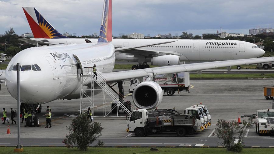 A woman exits a Philippine Airline plane at the airport in Manila, Philippines on Tuesday, Oct. 6, 2020. Philippine Airlines has called on its employees to apply for voluntary separation from the flag carrier in the first stage of a retrenchment plan it says may affect up to 35% of it's 7,000 strong work force largely due to the coronavirus pandemic. (AP Photo/Aaron Favila)