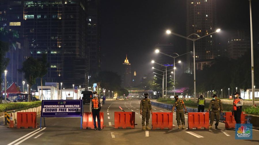 Seorang pedang kopi keliling melewati ruas jalan utama di kawasan jalan Sudirman-Thamrin, Jakarta, Sabtu (1/1/2022). Sejak pukul 22.00 WIB terpantau kendaraan dan warga  sangat lengang. 
Kendaraan operasional polisi tampak menyusuri ruas-ruas jalan yang menjadi titik penutupan jalan.Malam pergantian tahun 2021 menuju 2022 di pusat Kota Jakarta berlangsung sepi. Pemerintah Provinsi DKI Jakarta bersama Polda Metro Jaya menutup 11 ruas jalan sejak pukul 22.00 WIB.
Dari pantauan dilokasi sejumlah ruas jalan di Jakarta terpantau lengang. Tak banyak kendaraan melintas.   
Kendaraan operasional polisi tampak menyusuri ruas-ruas jalan yang menjadi titik penutupan jalan (CNBC Indonesia/ Tri Susilo)