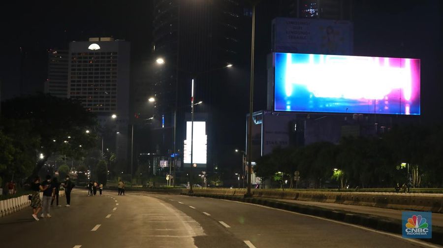 Seorang pedang kopi keliling melewati ruas jalan utama di kawasan jalan Sudirman-Thamrin, Jakarta, Sabtu (1/1/2022). Sejak pukul 22.00 WIB terpantau kendaraan dan warga  sangat lengang. 
Kendaraan operasional polisi tampak menyusuri ruas-ruas jalan yang menjadi titik penutupan jalan.Malam pergantian tahun 2021 menuju 2022 di pusat Kota Jakarta berlangsung sepi. Pemerintah Provinsi DKI Jakarta bersama Polda Metro Jaya menutup 11 ruas jalan sejak pukul 22.00 WIB.
Dari pantauan dilokasi sejumlah ruas jalan di Jakarta terpantau lengang. Tak banyak kendaraan melintas.   
Kendaraan operasional polisi tampak menyusuri ruas-ruas jalan yang menjadi titik penutupan jalan (CNBC Indonesia/ Tri Susilo)