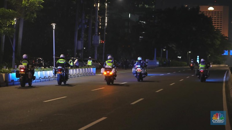 Seorang pedang kopi keliling melewati ruas jalan utama di kawasan jalan Sudirman-Thamrin, Jakarta, Sabtu (1/1/2022). Sejak pukul 22.00 WIB terpantau kendaraan dan warga  sangat lengang. 
Kendaraan operasional polisi tampak menyusuri ruas-ruas jalan yang menjadi titik penutupan jalan.Malam pergantian tahun 2021 menuju 2022 di pusat Kota Jakarta berlangsung sepi. Pemerintah Provinsi DKI Jakarta bersama Polda Metro Jaya menutup 11 ruas jalan sejak pukul 22.00 WIB.
Dari pantauan dilokasi sejumlah ruas jalan di Jakarta terpantau lengang. Tak banyak kendaraan melintas.   
Kendaraan operasional polisi tampak menyusuri ruas-ruas jalan yang menjadi titik penutupan jalan (CNBC Indonesia/ Tri Susilo)
