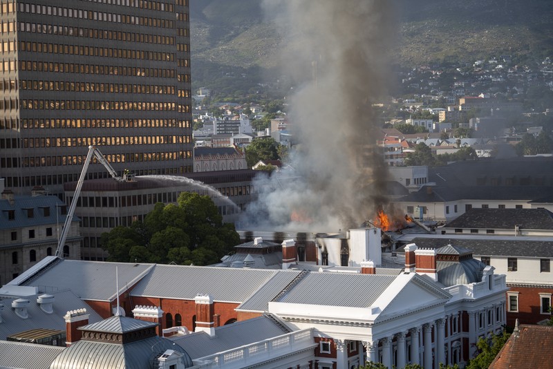 Petugas pemadam memadamkan lokasi kebakaran yang berada di gedung parlemen Cape Town, Afrika Selatan, Minggu (2/1/2022). (REUTERS/Mike Hutchings)