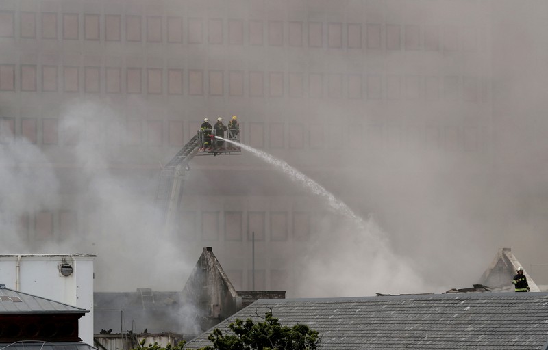 Petugas pemadam memadamkan lokasi kebakaran yang berada di gedung parlemen Cape Town, Afrika Selatan, Minggu (2/1/2022). (REUTERS/Mike Hutchings)