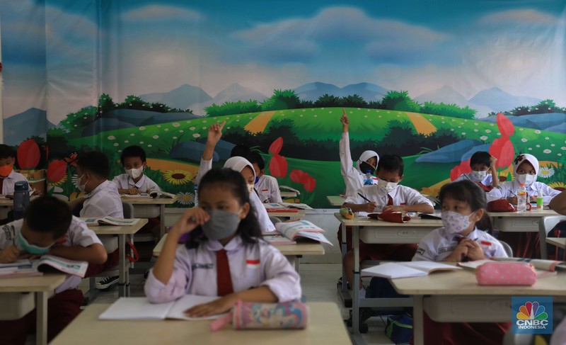 Sejumlah siswa-siswi mengikuti Pembelajaran Tatap Muka (PTM) di Sekolah Dasar Negeri (SDN) 01 Pondok Labu, Jakarta Selatan, Senin (3/1/2022). Pemerintah Provinsi (Pemprov) DKI Jakarta resmi menerapkan Pembelajaran Tatap Muka (PTM) dengan kapasitas 100 persen di seluruh sekolah mulai hari Senin (3/1). Relaksasi kebijakan ini sesuai dengan kondisi PPKM Level 1 yang diterapkan di Jakarta. Kepala bidang kesiswaan SD 01 Muhamad Nasir mengatakan, kebijakan tersebut merefleksikan Surat Keputusan Bersama (SKB) 4 Menteri yang diputuskan pada 21 Desember 2021. SKB dengan Nomor Nomor 05/KB/2021, Nomor 1347 Tahun 2021, Nomor HK.01.08/MENKES/6678/2021, Nomor 443-5847 Tahun 2021 berisi tentang Panduan Penyelenggaraan Pembelajaran di Masa Pandemi Covid-19. Meski dibuka 100 persen, Sekolah mewajibkan semua warga sekolah untuk menerapkan protokol kesehatan secara ketat. Terlebih lagi bagi mereka yang belum divaksinasi. Kebijakan PTM juga disambut baik bagi orang tua murid, Yulia salah satu orang tua murid kelas 2 mengatakan senang setelah dibuat PTM 100%. 