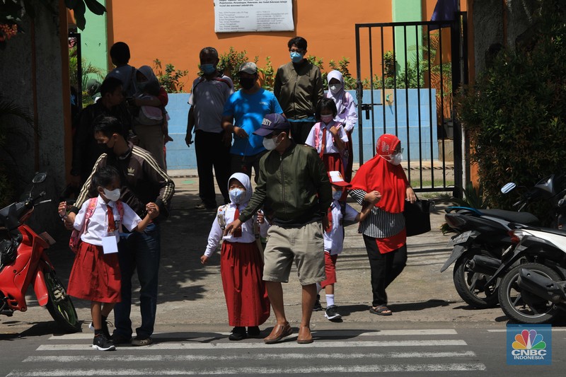 Sejumlah siswa-siswi mengikuti Pembelajaran Tatap Muka (PTM) di Sekolah Dasar Negeri (SDN) 01 Pondok Labu, Jakarta Selatan, Senin (3/1/2022). Pemerintah Provinsi (Pemprov) DKI Jakarta resmi menerapkan Pembelajaran Tatap Muka (PTM) dengan kapasitas 100 persen di seluruh sekolah mulai hari Senin (3/1). Relaksasi kebijakan ini sesuai dengan kondisi PPKM Level 1 yang diterapkan di Jakarta. Kepala bidang kesiswaan SD 01 Muhamad Nasir mengatakan, kebijakan tersebut merefleksikan Surat Keputusan Bersama (SKB) 4 Menteri yang diputuskan pada 21 Desember 2021. SKB dengan Nomor Nomor 05/KB/2021, Nomor 1347 Tahun 2021, Nomor HK.01.08/MENKES/6678/2021, Nomor 443-5847 Tahun 2021 berisi tentang Panduan Penyelenggaraan Pembelajaran di Masa Pandemi Covid-19. Meski dibuka 100 persen, Sekolah mewajibkan semua warga sekolah untuk menerapkan protokol kesehatan secara ketat. Terlebih lagi bagi mereka yang belum divaksinasi. Kebijakan PTM juga disambut baik bagi orang tua murid, Yulia salah satu orang tua murid kelas 2 mengatakan senang setelah dibuat PTM 100%. 