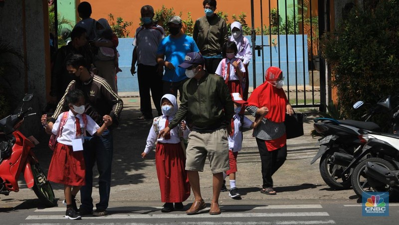 Sejumlah siswa-siswi mengikuti Pembelajaran Tatap Muka (PTM) di Sekolah Dasar Negeri (SDN) 01 Pondok Labu, Jakarta Selatan, Senin (3/1/2022). Pemerintah Provinsi (Pemprov) DKI Jakarta resmi menerapkan Pembelajaran Tatap Muka (PTM) dengan kapasitas 100 persen di seluruh sekolah mulai hari Senin (3/1). Relaksasi kebijakan ini sesuai dengan kondisi PPKM Level 1 yang diterapkan di Jakarta. Kepala bidang kesiswaan SD 01 Muhamad Nasir mengatakan, kebijakan tersebut merefleksikan Surat Keputusan Bersama (SKB) 4 Menteri yang diputuskan pada 21 Desember 2021. SKB dengan Nomor Nomor 05/KB/2021, Nomor 1347 Tahun 2021, Nomor HK.01.08/MENKES/6678/2021, Nomor 443-5847 Tahun 2021 berisi tentang Panduan Penyelenggaraan Pembelajaran di Masa Pandemi Covid-19. Meski dibuka 100 persen, Sekolah mewajibkan semua warga sekolah untuk menerapkan protokol kesehatan secara ketat. Terlebih lagi bagi mereka yang belum divaksinasi. Kebijakan PTM juga disambut baik bagi orang tua murid, Yulia salah satu orang tua murid kelas 2 mengatakan senang setelah dibuat PTM 100%. 