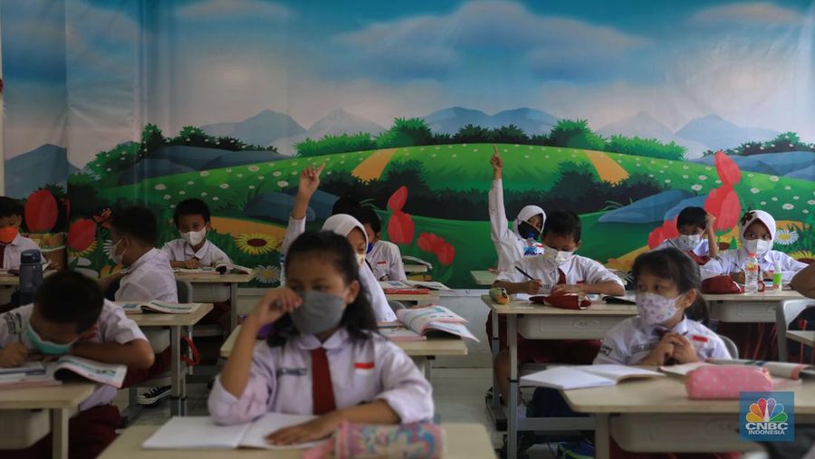 Sejumlah siswa-siswi mengikuti Pembelajaran Tatap Muka (PTM) di Sekolah Dasar Negeri (SDN) 01 Pondok Labu, Jakarta Selatan, Senin (3/1/2022). Pemerintah Provinsi (Pemprov) DKI Jakarta resmi menerapkan Pembelajaran Tatap Muka (PTM) dengan kapasitas 100 persen di seluruh sekolah mulai hari Senin (3/1). Relaksasi kebijakan ini sesuai dengan kondisi PPKM Level 1 yang diterapkan di Jakarta. Kepala bidang kesiswaan SD 01 Muhamad Nasir mengatakan, kebijakan tersebut merefleksikan Surat Keputusan Bersama (SKB) 4 Menteri yang diputuskan pada 21 Desember 2021. SKB dengan Nomor Nomor 05/KB/2021, Nomor 1347 Tahun 2021, Nomor HK.01.08/MENKES/6678/2021, Nomor 443-5847 Tahun 2021 berisi tentang Panduan Penyelenggaraan Pembelajaran di Masa Pandemi Covid-19. Meski dibuka 100 persen, Sekolah mewajibkan semua warga sekolah untuk menerapkan protokol kesehatan secara ketat. Terlebih lagi bagi mereka yang belum divaksinasi. Kebijakan PTM juga disambut baik bagi orang tua murid, Yulia salah satu orang tua murid kelas 2 mengatakan senang setelah dibuat PTM 100%. 