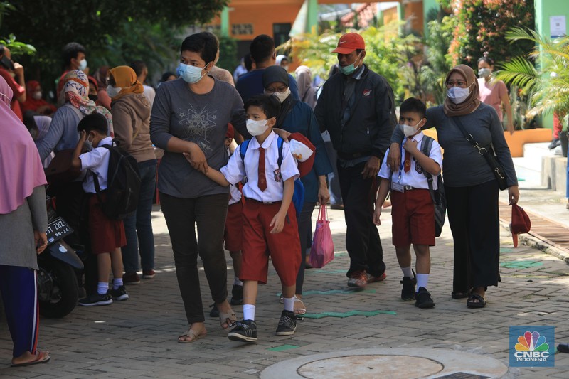 Sejumlah siswa-siswi mengikuti Pembelajaran Tatap Muka (PTM) di Sekolah Dasar Negeri (SDN) 01 Pondok Labu, Jakarta Selatan, Senin (3/1/2022). Pemerintah Provinsi (Pemprov) DKI Jakarta resmi menerapkan Pembelajaran Tatap Muka (PTM) dengan kapasitas 100 persen di seluruh sekolah mulai hari Senin (3/1). Relaksasi kebijakan ini sesuai dengan kondisi PPKM Level 1 yang diterapkan di Jakarta. Kepala bidang kesiswaan SD 01 Muhamad Nasir mengatakan, kebijakan tersebut merefleksikan Surat Keputusan Bersama (SKB) 4 Menteri yang diputuskan pada 21 Desember 2021. SKB dengan Nomor Nomor 05/KB/2021, Nomor 1347 Tahun 2021, Nomor HK.01.08/MENKES/6678/2021, Nomor 443-5847 Tahun 2021 berisi tentang Panduan Penyelenggaraan Pembelajaran di Masa Pandemi Covid-19. Meski dibuka 100 persen, Sekolah mewajibkan semua warga sekolah untuk menerapkan protokol kesehatan secara ketat. Terlebih lagi bagi mereka yang belum divaksinasi. Kebijakan PTM juga disambut baik bagi orang tua murid, Yulia salah satu orang tua murid kelas 2 mengatakan senang setelah dibuat PTM 100%. 