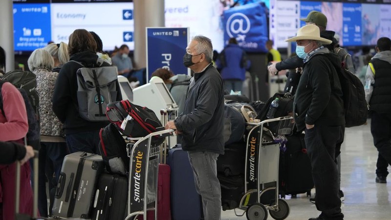 Penumpang mengantre di pos pemeriksaan keamanan di terminal utama Bandara Internasional Denver di Denver, Senin (3/1/2022).  (AP/David Zalubowski)