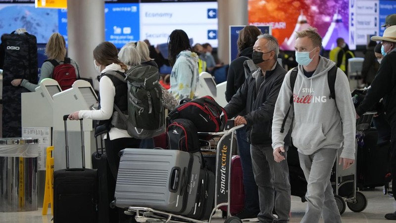 Penumpang mengantre di pos pemeriksaan keamanan di terminal utama Bandara Internasional Denver di Denver, Senin (3/1/2022).  (AP/David Zalubowski)