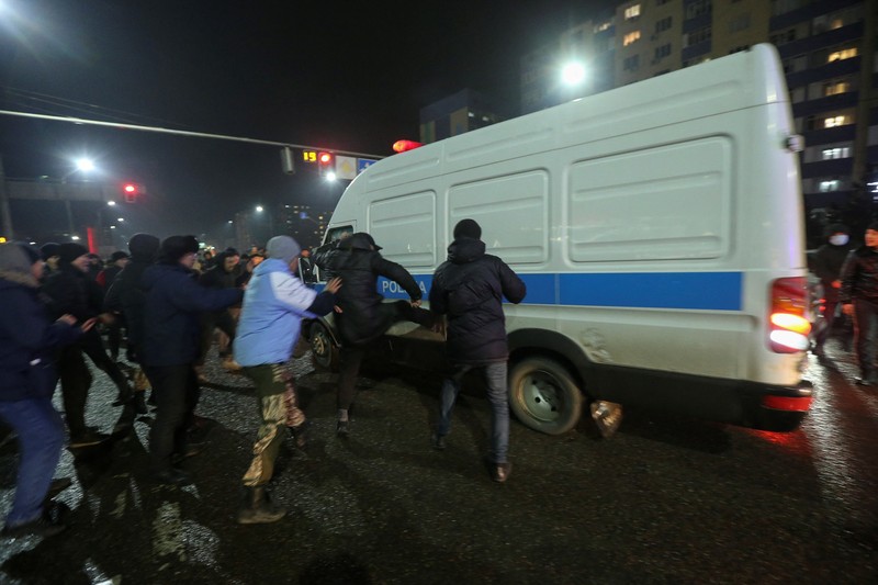 Demo Protes Kenaikkan Bahan Bahar gas Cair LPG di Almaty, Kazakhstan Orang-orang menyerang minivan polisi saat protes terhadap kenaikan biaya LPG menyusul keputusan otoritas Kazakh untuk mengangkat batas harga bahan bakar gas cair di Almaty, Kazakhstan (5/1/2022). (REUTERS/Pavel Mikheyev)