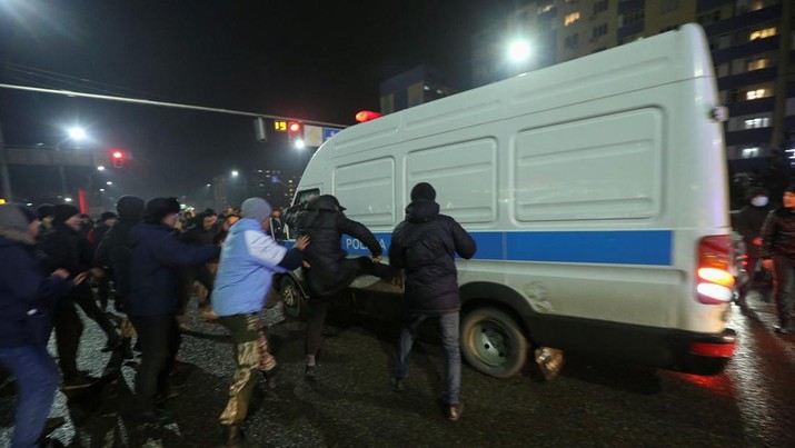 Orang-orang menyerang minivan polisi saat protes terhadap kenaikan biaya LPG menyusul keputusan otoritas Kazakh untuk mengangkat batas harga bahan bakar gas cair di Almaty, Kazakhstan (5/1/2022). (REUTERS/Pavel Mikheyev)
