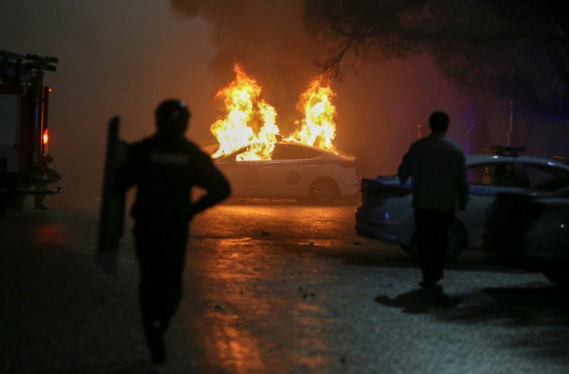 Orang-orang menyerang minivan polisi saat protes terhadap kenaikan biaya LPG menyusul keputusan otoritas Kazakh untuk mengangkat batas harga bahan bakar gas cair di Almaty, Kazakhstan (5/1/2022). (REUTERS/Pavel Mikheyev)