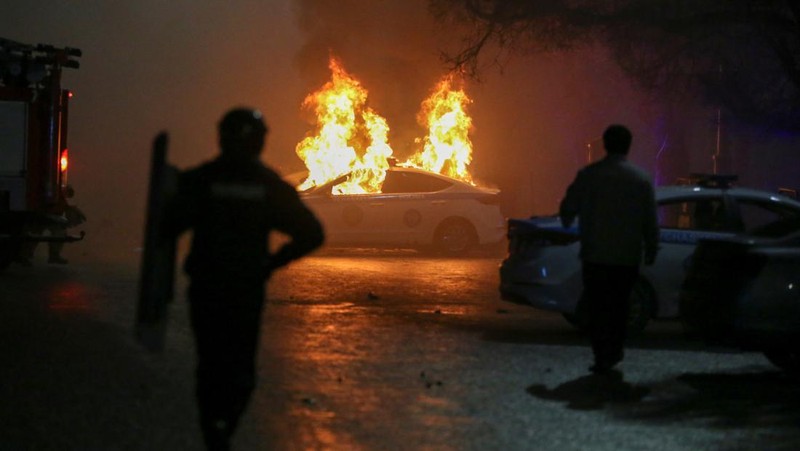Orang-orang menyerang minivan polisi saat protes terhadap kenaikan biaya LPG menyusul keputusan otoritas Kazakh untuk mengangkat batas harga bahan bakar gas cair di Almaty, Kazakhstan (5/1/2022). (REUTERS/Pavel Mikheyev)