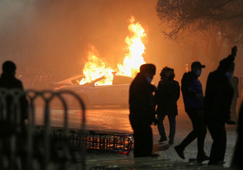 Orang-orang menyerang minivan polisi saat protes terhadap kenaikan biaya LPG menyusul keputusan otoritas Kazakh untuk mengangkat batas harga bahan bakar gas cair di Almaty, Kazakhstan (5/1/2022). (REUTERS/Pavel Mikheyev)