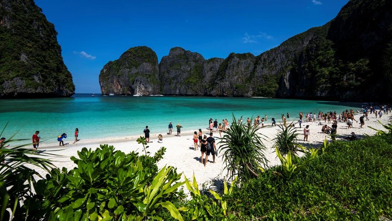Turis mengunjungi teluk Maya setelah Thailand membuka kembali pantainya yang terkenal di dunia setelah ditutup selama lebih dari tiga tahun untuk pemulihan ekosistem dari dampak overtourism di provinsi Krabi, Thailand, Selasa (3/1/2022). (REUTERS/Athit Perawongmetha)