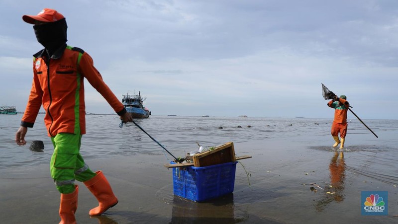 Petugas PPSU membersihkan sampah setelah terjadi banjir rob di Pelabuhan Kali Adem, Muara Angke, Jakarta, Jumat (7/1/2022). Setelah terendam banjir rob, petugas PPSU tetap sigap bersihkan sampah yang mengambang terbawa air laut. Suku Dinas Lingkungan Hidup (LH) Kota Administrasi Jakarta Utara membentuk tim khusus yang bertugas untuk menangani sampah pasca banjir rob yang terjadi di beberapa wilayah seperti di Muara Angke dan Sunda Kelapa. Menurut petugas PPSU 