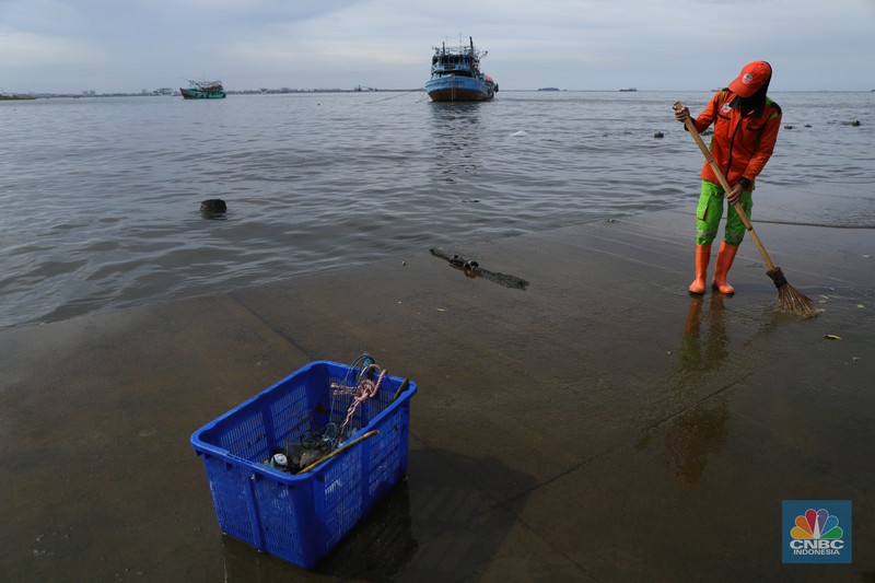 Petugas PPSU membersihkan sampah setelah terjadi banjir rob di Pelabuhan Kali Adem, Muara Angke, Jakarta, Jumat (7/1/2022). Setelah terendam banjir rob, petugas PPSU tetap sigap bersihkan sampah yang mengambang terbawa air laut. Suku Dinas Lingkungan Hidup (LH) Kota Administrasi Jakarta Utara membentuk tim khusus yang bertugas untuk menangani sampah pasca banjir rob yang terjadi di beberapa wilayah seperti di Muara Angke dan Sunda Kelapa. Menurut petugas PPSU 