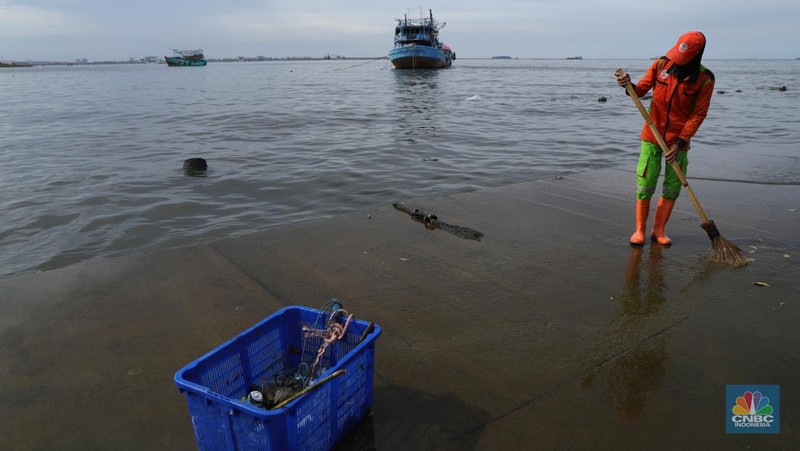 Petugas PPSU membersihkan sampah setelah terjadi banjir rob di Pelabuhan Kali Adem, Muara Angke, Jakarta, Jumat (7/1/2022). Setelah terendam banjir rob, petugas PPSU tetap sigap bersihkan sampah yang mengambang terbawa air laut. Suku Dinas Lingkungan Hidup (LH) Kota Administrasi Jakarta Utara membentuk tim khusus yang bertugas untuk menangani sampah pasca banjir rob yang terjadi di beberapa wilayah seperti di Muara Angke dan Sunda Kelapa. Menurut petugas PPSU 