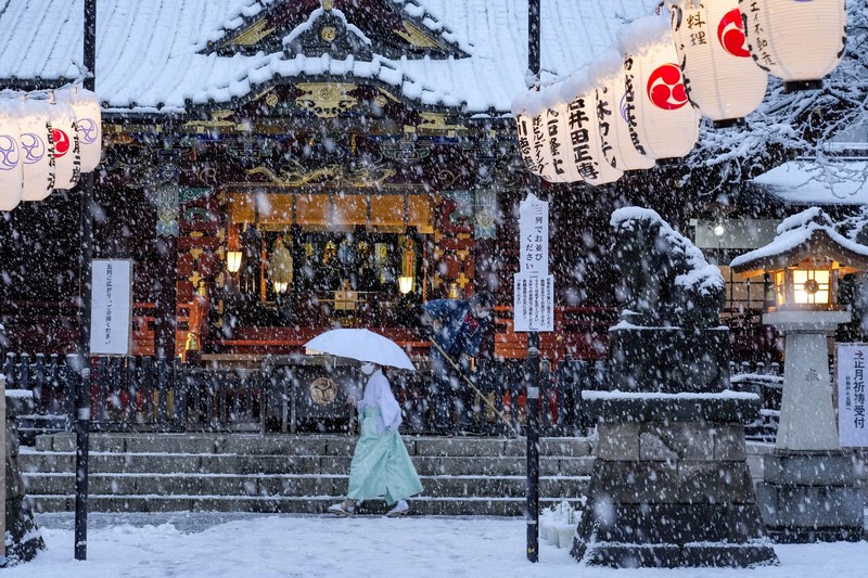 Seseorang mengendarai sepeda saat salju turun di Tokyo, Jepang Kamis (6/1/2022). (AP/Kiichiro Sato)