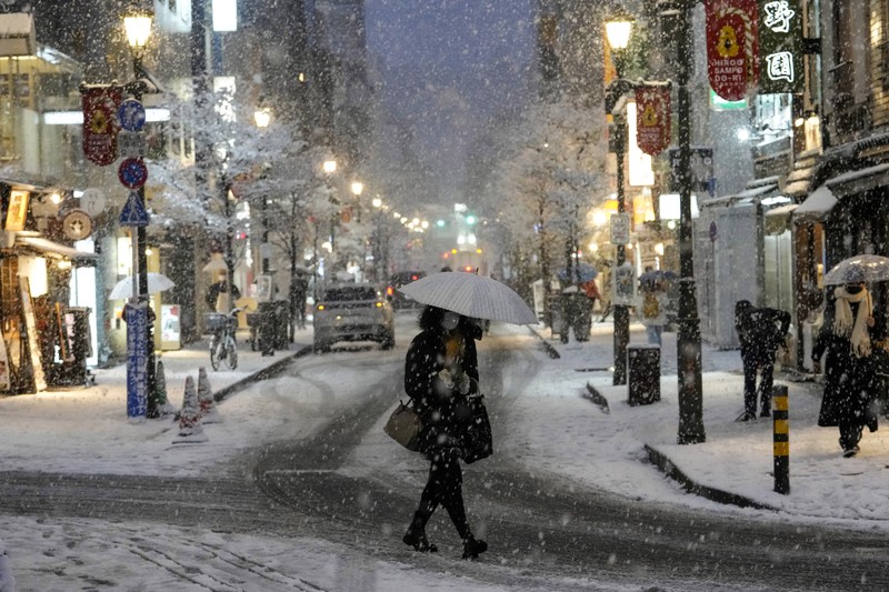 Seseorang mengendarai sepeda saat salju turun di Tokyo, Jepang Kamis (6/1/2022). (AP/Kiichiro Sato)