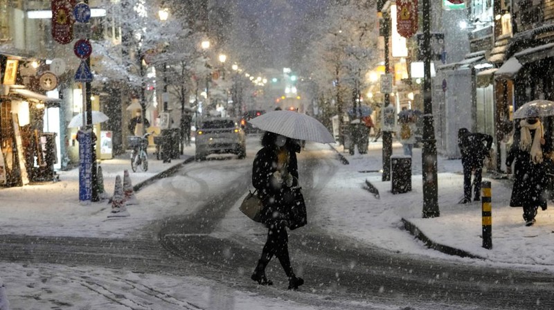 Seseorang mengendarai sepeda saat salju turun di Tokyo, Jepang Kamis (6/1/2022). (AP/Kiichiro Sato)