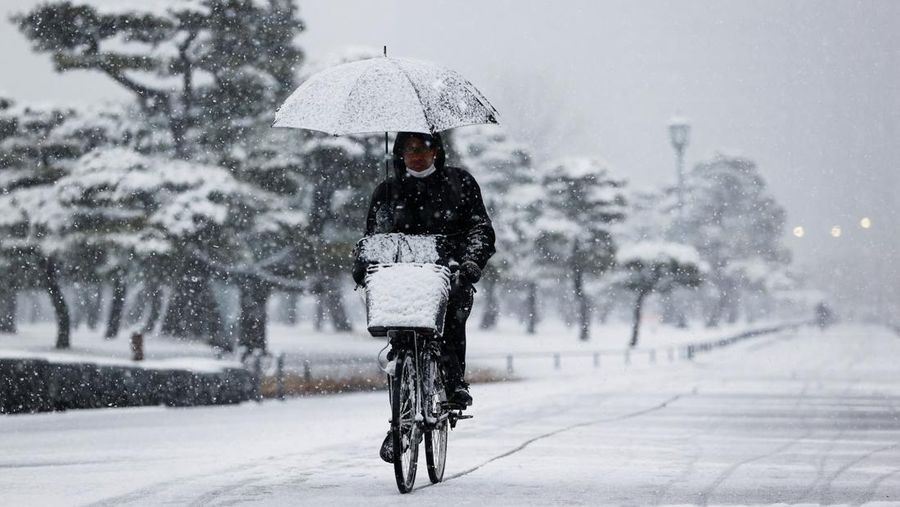 Seseorang mengendarai sepeda saat salju turun di Tokyo, Jepang Kamis (6/1/2022). (AP/Kiichiro Sato)