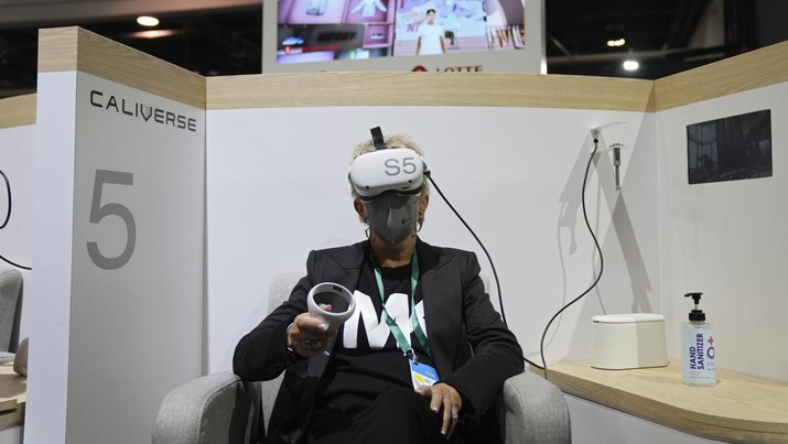 FILE - Kelly Taylor tries out a metaverse virtual shopping experience at the LOTTE Data Communication booth during the CES tech show Wednesday, Jan. 5, 2022, in Las Vegas. The thousands of people who gathered in Las Vegas for this week's CES gadget show were a fraction of the usual crowd for the influential tech conference, the event's organizer said Friday, Jan. 7. The Consumer Technology Association said on the show's closing day that more than 40,000 people attended the multi-day event on the Las Vegas Strip. (AP Photo/Joe Buglewicz, File)