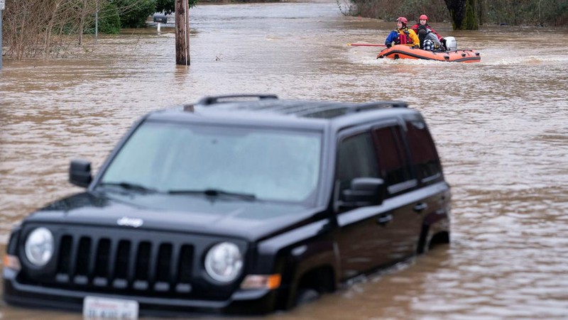 Chehalis fire and rescue team members bring a stranded resident to dry land after floodwaters threatened their home following heavy rain in Chehalis, Washington, U.S., January 7, 2022. REUTERS/Nathan Howard
