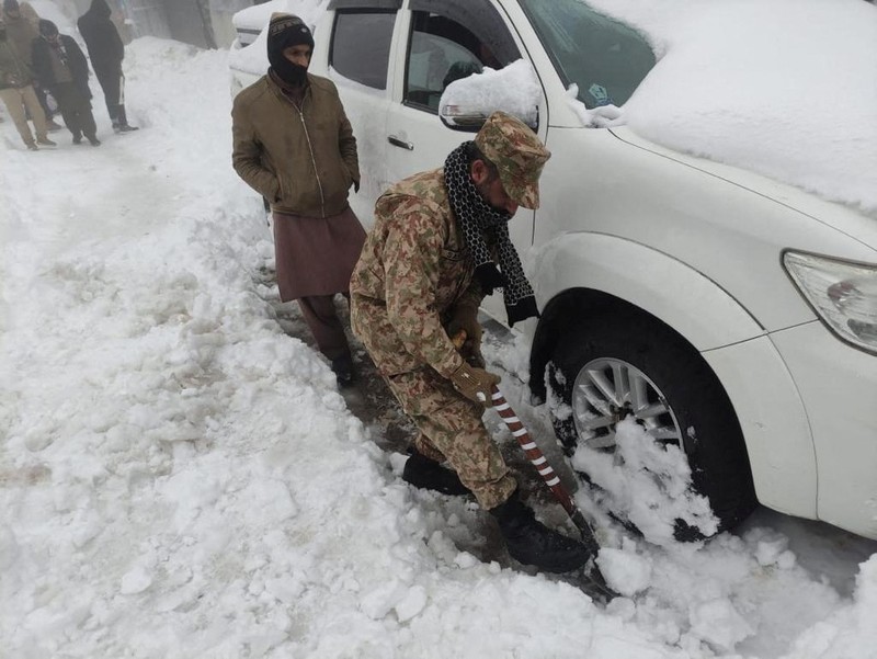 Kendaraan terjebak pohon tumbang di jalan bersalju Murree, timur laut Islamabad, Pakistan, Sabtu (8/1/2022). (via REUTERS/ISPR)