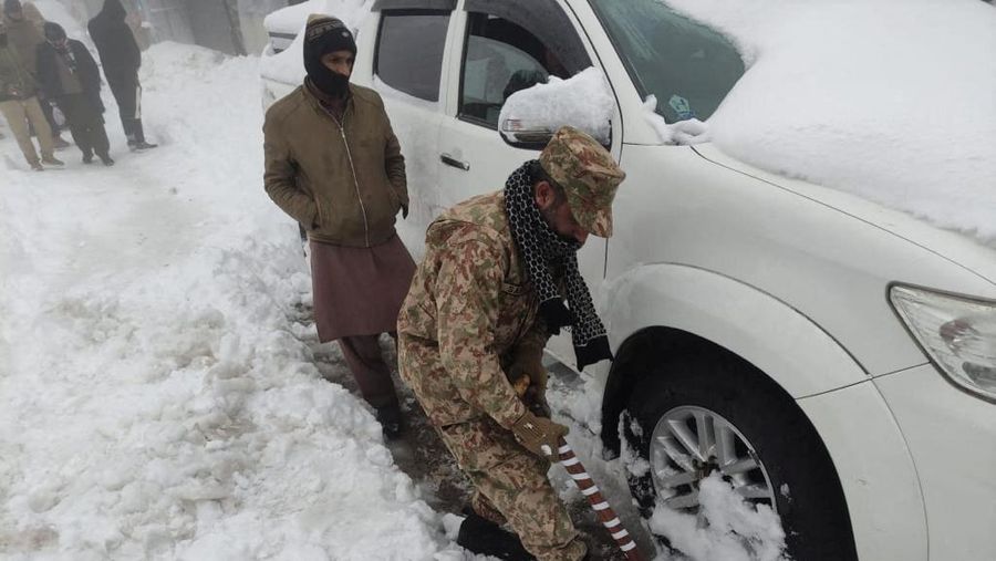 Kendaraan terjebak pohon tumbang di jalan bersalju Murree, timur laut Islamabad, Pakistan, Sabtu (8/1/2022). (via REUTERS/ISPR)