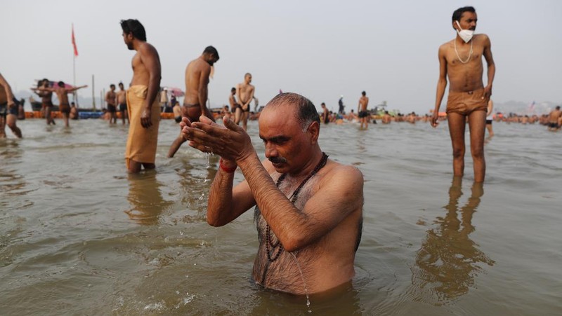 Hindu devotees crowd the Sangam, the confluence of three rivers — the Ganges, the Yamuna and the mythical Saraswati, to take a ritualistic bath during Makar Sankranti festival that falls during the annual traditional fair of Magh Mela festival, one of the most sacred pilgrimages in Hinduism, in Prayagraj, India. Friday, Jan. 14, 2022. Tens of thousands of devout Hindus, led by heads of monasteries and ash-smeared ascetics, took a holy dip into the frigid waters on Friday despite rising COVID-19 infections in the country. (AP Photo/Rajesh Kumar Singh)