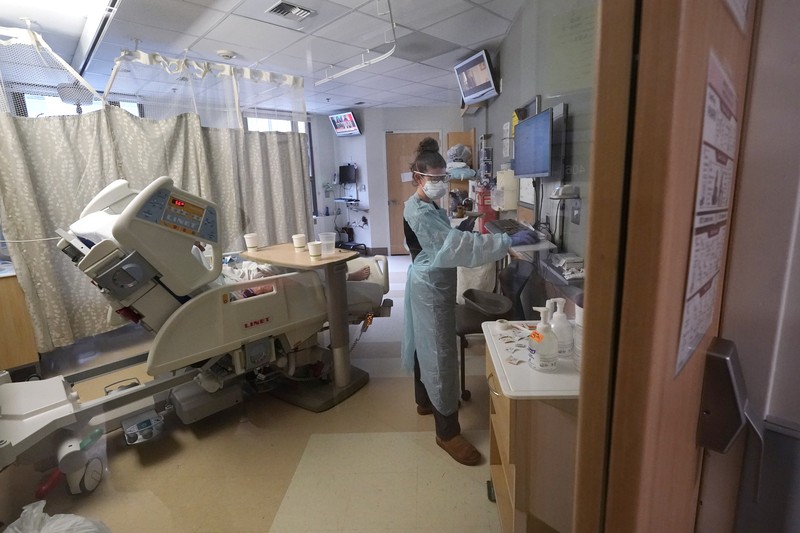 APTOPIX Virus Outbreak Washington Registered nurse Jessalynn Dest, left, removes protective equipment and washes her hands after leaving a COVID-19 patient's room as speech therapist Sam Gibbs puts on safety clothing while preparing to see a patient in the acute care unit of Harborview Medical Center, Friday, Jan. 14, 2022, in Seattle. Washington Gov. Jay Inslee is deploying 100 members of the state National Guard to hospitals across the state amid staff shortages due to an omicron-fueled spike in COVID-19 hospitalizations. Inslee announced Thursday that teams will be deployed to assist four overcrowded emergency departments at hospitals in Everett, Yakima, Wenatchee and Spokane, and that testing teams will be based at hospitals in Olympia, Richland, Seattle and Tacoma. (AP Photo/Elaine Thompson)