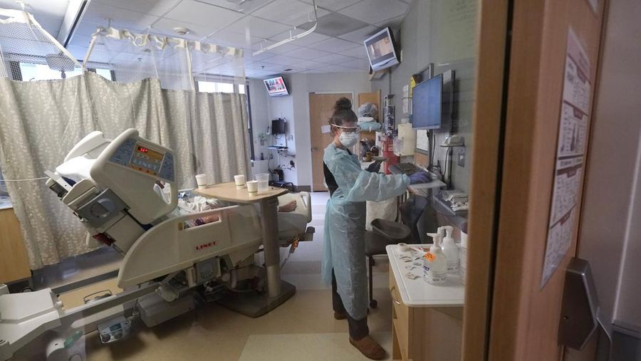 Registered nurse Jessalynn Dest fills out records while treating a COVID-19 patient in the acute care unit of Harborview Medical Center, Friday, Jan. 14, 2022, in Seattle. Washington Gov. Jay Inslee is deploying 100 members of the state National Guard to hospitals across the state amid staff shortages due to an omicron-fueled spike in COVID-19 hospitalizations. Inslee announced Thursday that teams will be deployed to assist four overcrowded emergency departments at hospitals in Everett, Yakima, Wenatchee and Spokane, and that testing teams will be based at hospitals in Olympia, Richland, Seattle and Tacoma. (AP Photo/Elaine Thompson)
