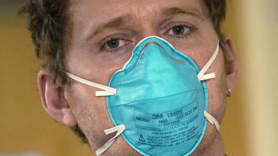 Registered nurse Scott McGieson wears an N95 mask as he walks out of a patient's room in the acute care unit of Harborview Medical Center, Friday, Jan. 14, 2022, in Seattle. Washington Gov. Jay Inslee is deploying 100 members of the state National Guard to hospitals across the state amid staff shortages due to an omicron-fueled spike in COVID-19 hospitalizations. Inslee announced Thursday that teams will be deployed to assist four overcrowded emergency departments at hospitals in Everett, Yakima, Wenatchee and Spokane, and that testing teams will be based at hospitals in Olympia, Richland, Seattle and Tacoma. (AP Photo/Elaine Thompson)