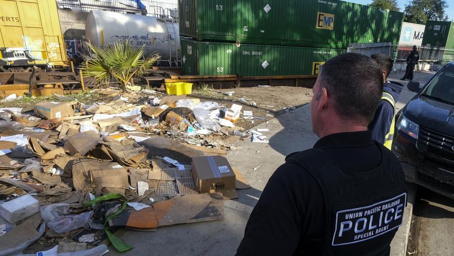Pekerja kontraktor Adam Rodriguez (depan) dan Luis Rosas mengambil ban kendaraan dari kotak dan paket yang robek di sepanjang bagian rel kereta Union Pacific di pusat kota Los Angeles Jumat (14/1/2022).  Pencuri telah merampok kontainer kargo di atas kereta dekat pusat kota Los Angeles selama berbulan-bulan dan juga mereka meninggalkan ratusan kardus dan barang-barang yang menurut para pencuri tidak cukup berharga untuk diambil. (AP/Ringo H.W. Chiu)