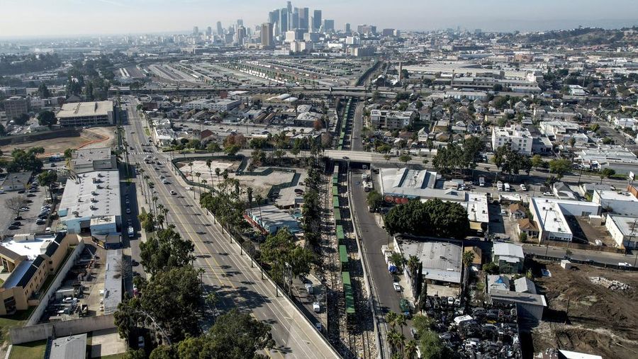 Pekerja kontraktor Adam Rodriguez (depan) dan Luis Rosas mengambil ban kendaraan dari kotak dan paket yang robek di sepanjang bagian rel kereta Union Pacific di pusat kota Los Angeles Jumat (14/1/2022).  Pencuri telah merampok kontainer kargo di atas kereta dekat pusat kota Los Angeles selama berbulan-bulan dan juga mereka meninggalkan ratusan kardus dan barang-barang yang menurut para pencuri tidak cukup berharga untuk diambil. (AP/Ringo H.W. Chiu)