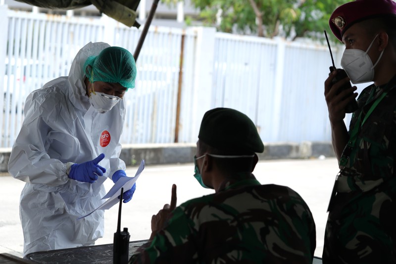 Petugas ambulans memberikan data pasien Covid-19  kepada petugas jaga di Wisma Atlet, Jakarta, Senin (17/1/2022). (CNBC Indonesia/Tri Susilo)