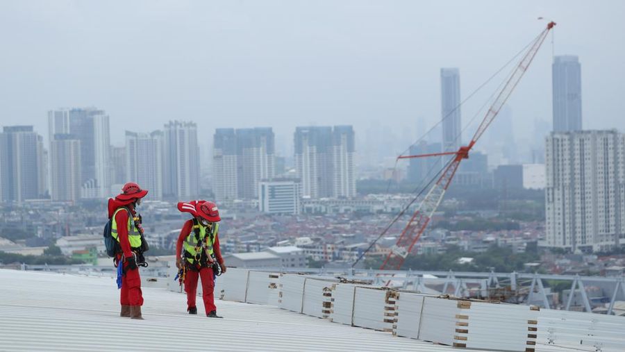 Pekerja mengangkat panel surya di atas atap Stadion  Jakarta Internasional Stadium (JIS) di Jakarta, Selasa (18/1/2022).  (CNBC Indonesia/Tri Susilo)