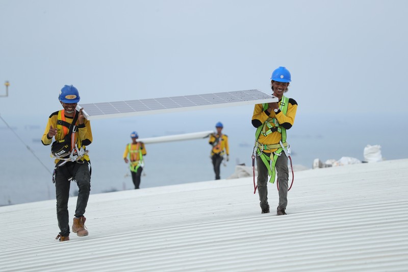 Pekerja mengangkat panel surya di atas atap Stadion  Jakarta Internasional Stadium (JIS) di Jakarta, Selasa (18/1/2022).  (CNBC Indonesia/Tri Susilo)