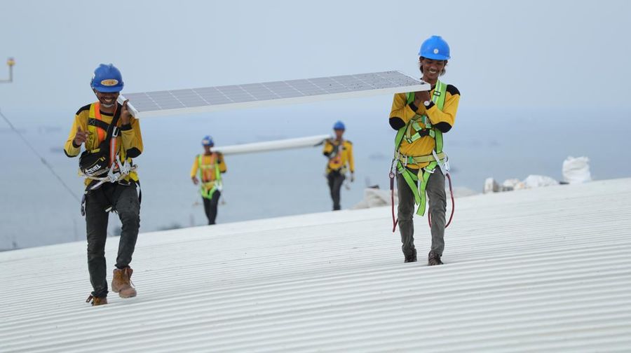 Pekerja mengangkat panel surya di atas atap Stadion  Jakarta Internasional Stadium (JIS) di Jakarta, Selasa (18/1/2022).  (CNBC Indonesia/Tri Susilo)