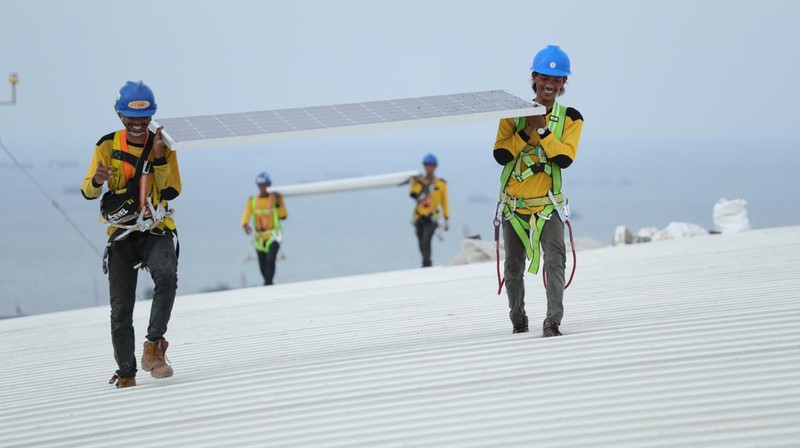 Pekerja mengangkat panel surya di atas atap Stadion  Jakarta Internasional Stadium (JIS) di Jakarta, Selasa (18/1/2022).  (CNBC Indonesia/Tri Susilo)