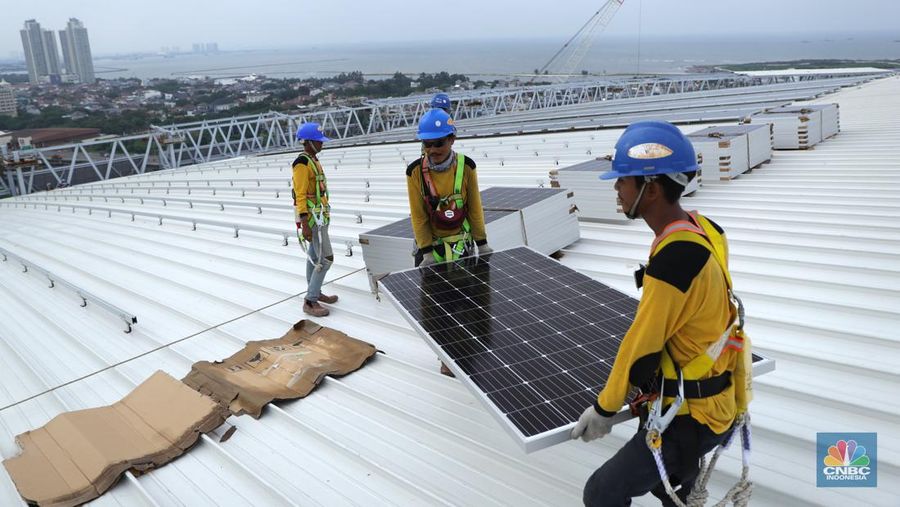 Pekerja mengangkat panel surya di atas atap Stadion  Jakarta Internasional Stadium (JIS) di Jakarta, Selasa (18/1/2022).  (CNBC Indonesia/Tri Susilo)