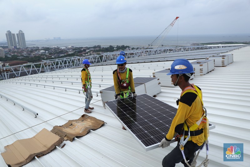 Pekerja mengangkat panel surya di atas atap Stadion  Jakarta Internasional Stadium (JIS) di Jakarta, Selasa (18/1/2022).  (CNBC Indonesia/Tri Susilo)