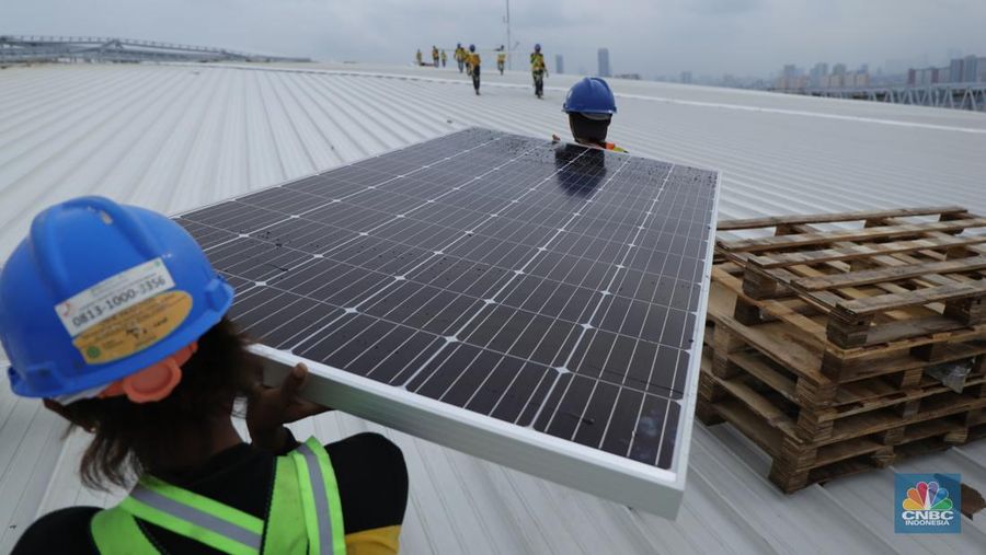 Pekerja mengangkat panel surya di atas atap Stadion  Jakarta Internasional Stadium (JIS) di Jakarta, Selasa (18/1/2022).  (CNBC Indonesia/Tri Susilo)