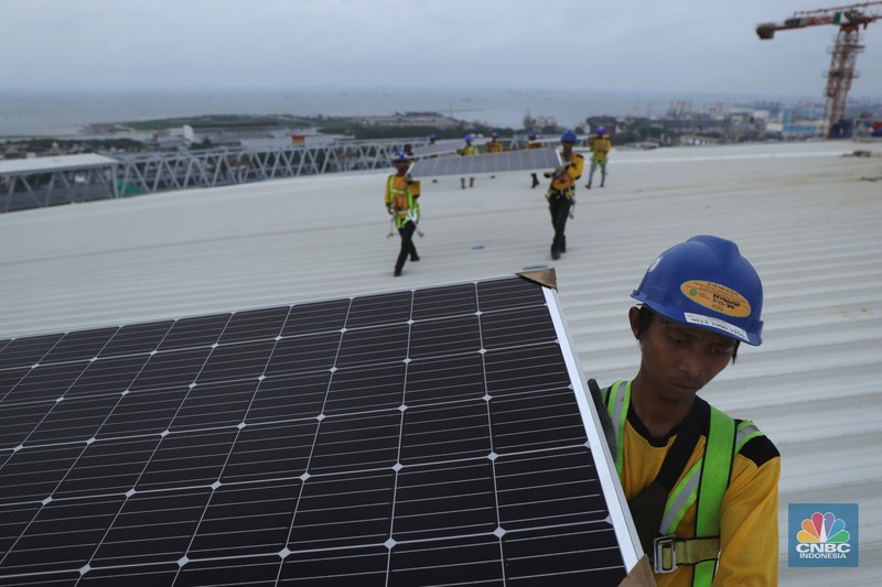 Pekerja mengangkat panel surya di atas atap Stadion  Jakarta Internasional Stadium (JIS) di Jakarta, Selasa (18/1/2022).  (CNBC Indonesia/Tri Susilo)