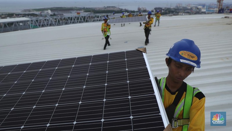 Pekerja mengangkat panel surya di atas atap Stadion  Jakarta Internasional Stadium (JIS) di Jakarta, Selasa (18/1/2022).  (CNBC Indonesia/Tri Susilo)