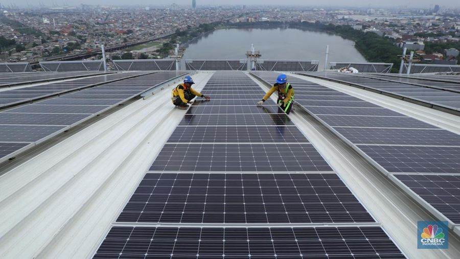 Pekerja mengangkat panel surya di atas atap Stadion  Jakarta Internasional Stadium (JIS) di Jakarta, Selasa (18/1/2022).  (CNBC Indonesia/Tri Susilo)