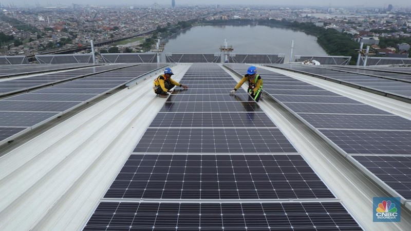 Pekerja mengangkat panel surya di atas atap Stadion  Jakarta Internasional Stadium (JIS) di Jakarta, Selasa (18/1/2022).  (CNBC Indonesia/Tri Susilo)